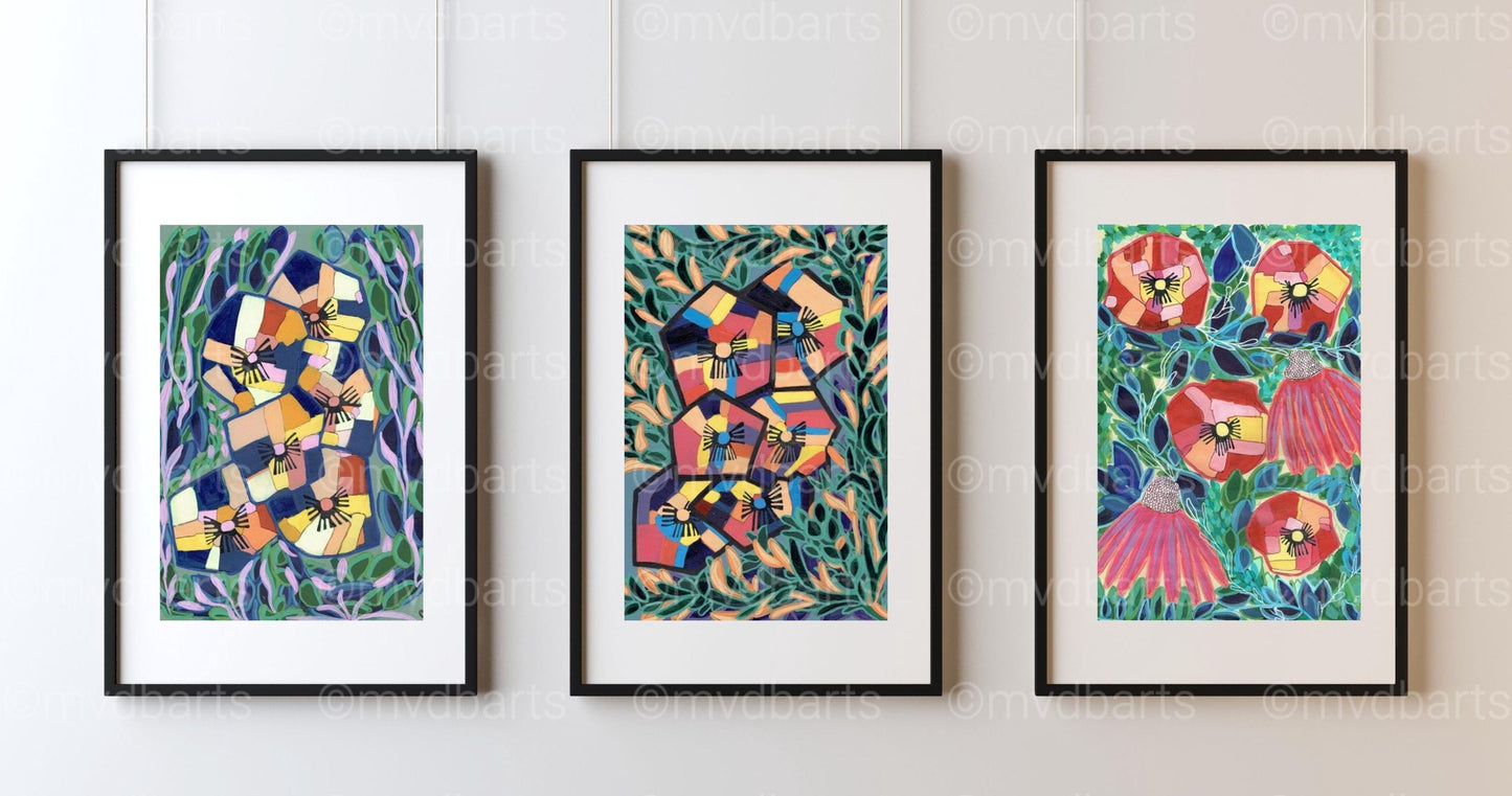 Three framed abstract floral art prints are displayed side-by-side on a white paneled wall. The prints feature vibrant, colorful abstract patterns with green leaves and red, yellow, and blue floral elements, enclosed in black frames with white mats.